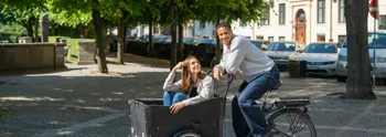 To unge mennesker i ladcykel foran park