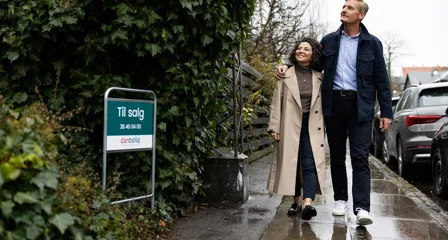 Par går på en villavej forbi et "Til salg"-skilt fra danbolig